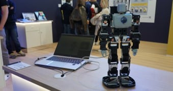 Small robot standing on table exhibited at a tradeshow