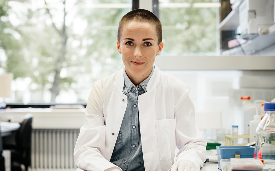Woman scientist in a laboratory wearing a white coat with equipment around.