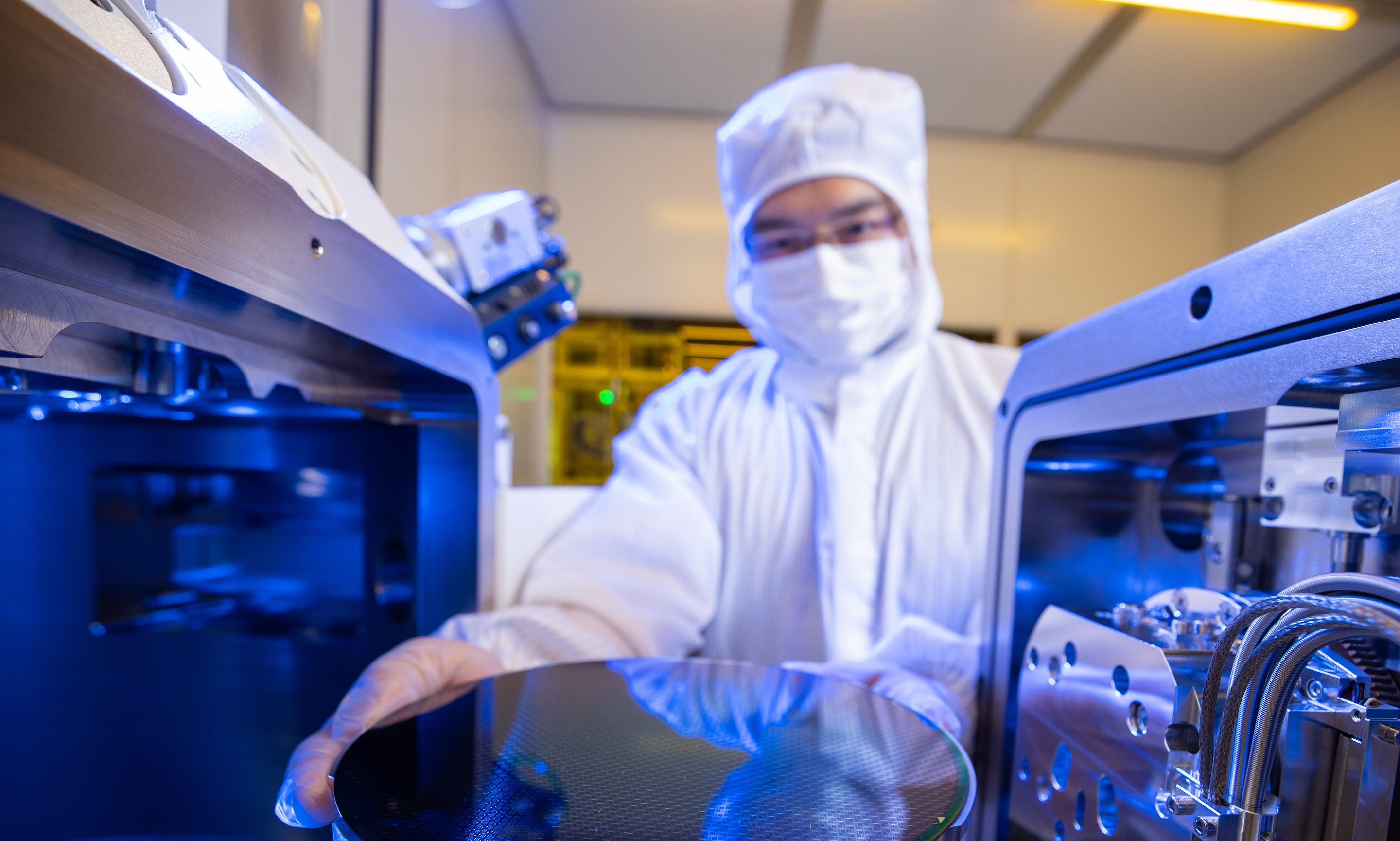 Cleanroom technician handling semiconductor wafer.