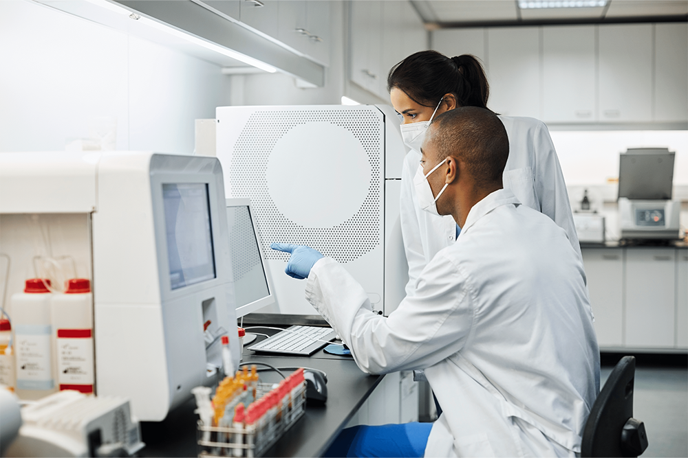 Image of two scientists wearing lab coats and face masks working in a laboratory.