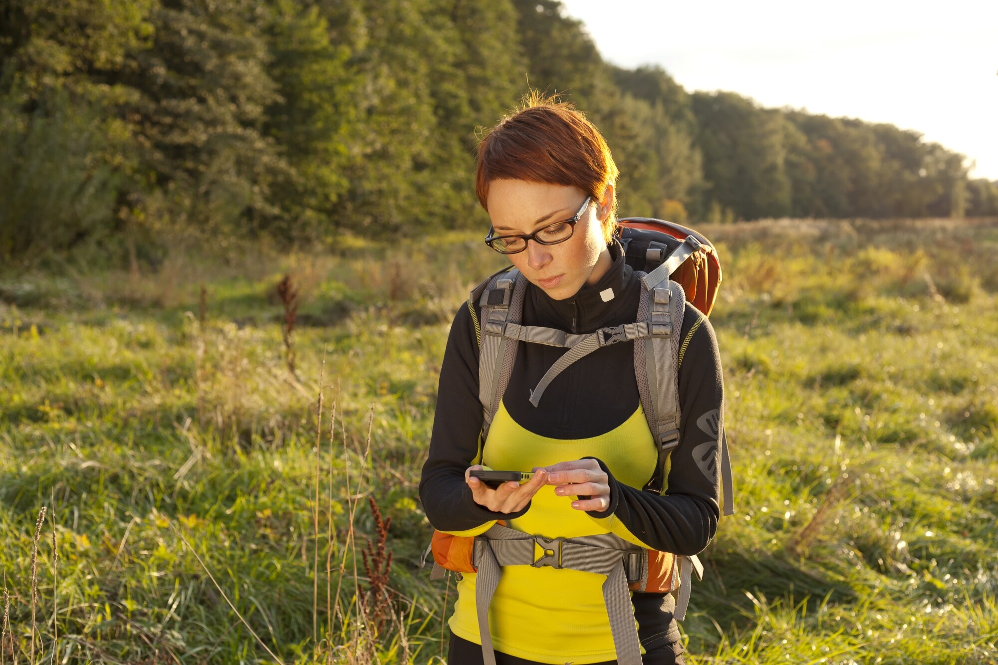 Woman hiking along a forest trail, holding an e-compass. 