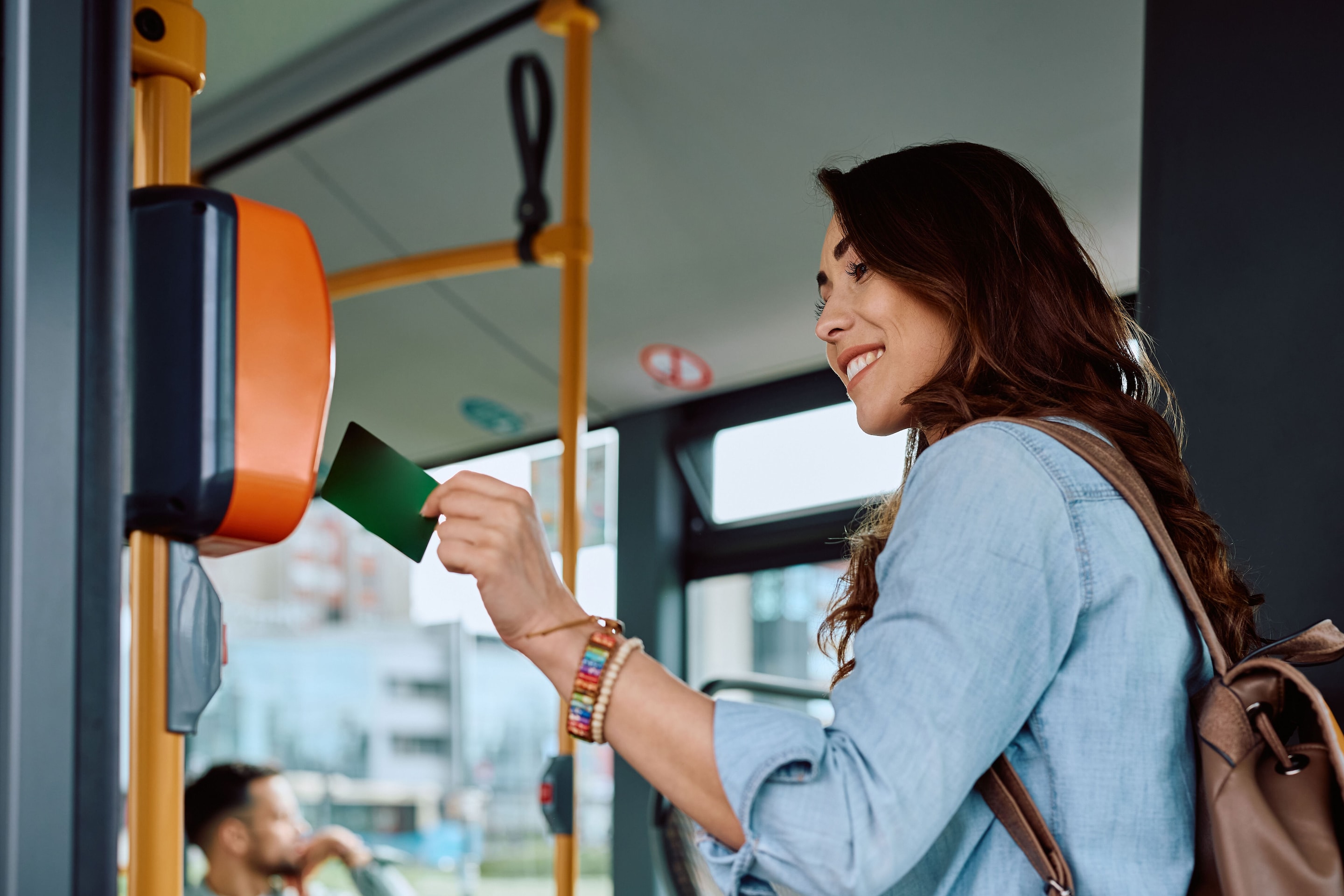 Person tapping a card on a contactless reader inside a bus.
