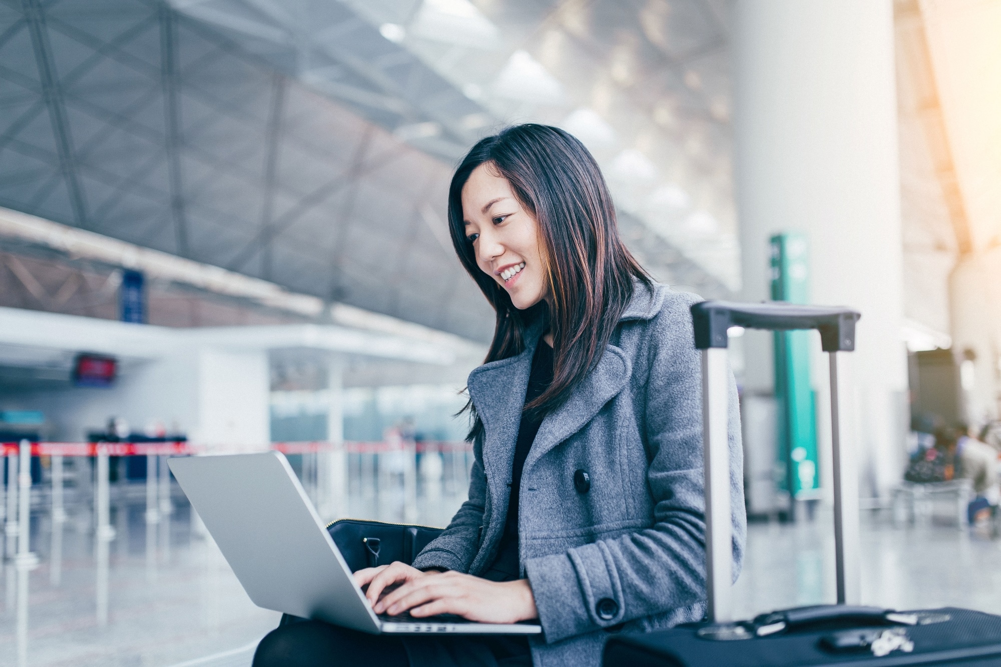 Woman using laptop in an airport terminal with ST EEPROM logo.