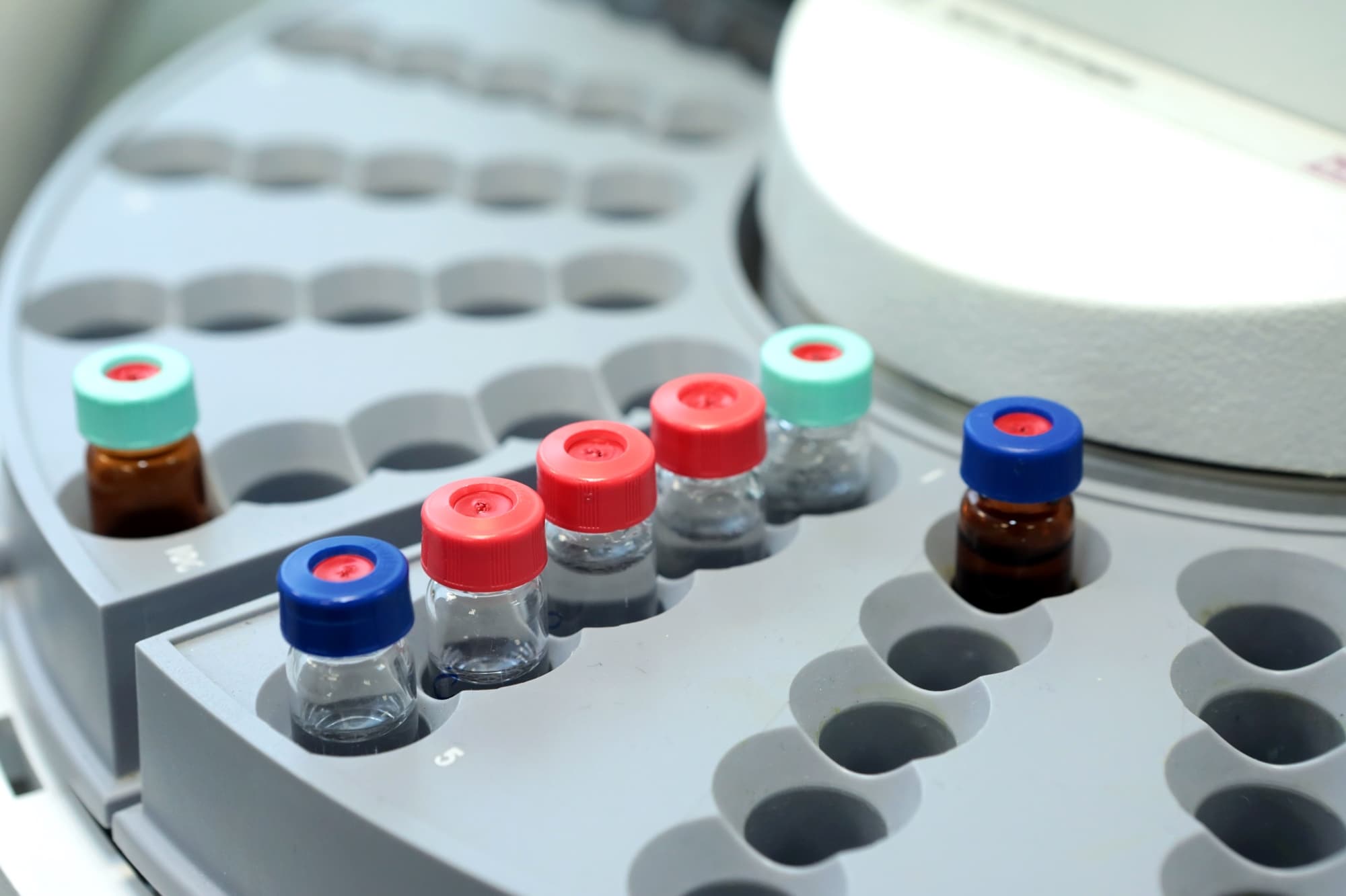 Close-up of a laboratory centrifuge rotor holding several small vials with colored caps. 