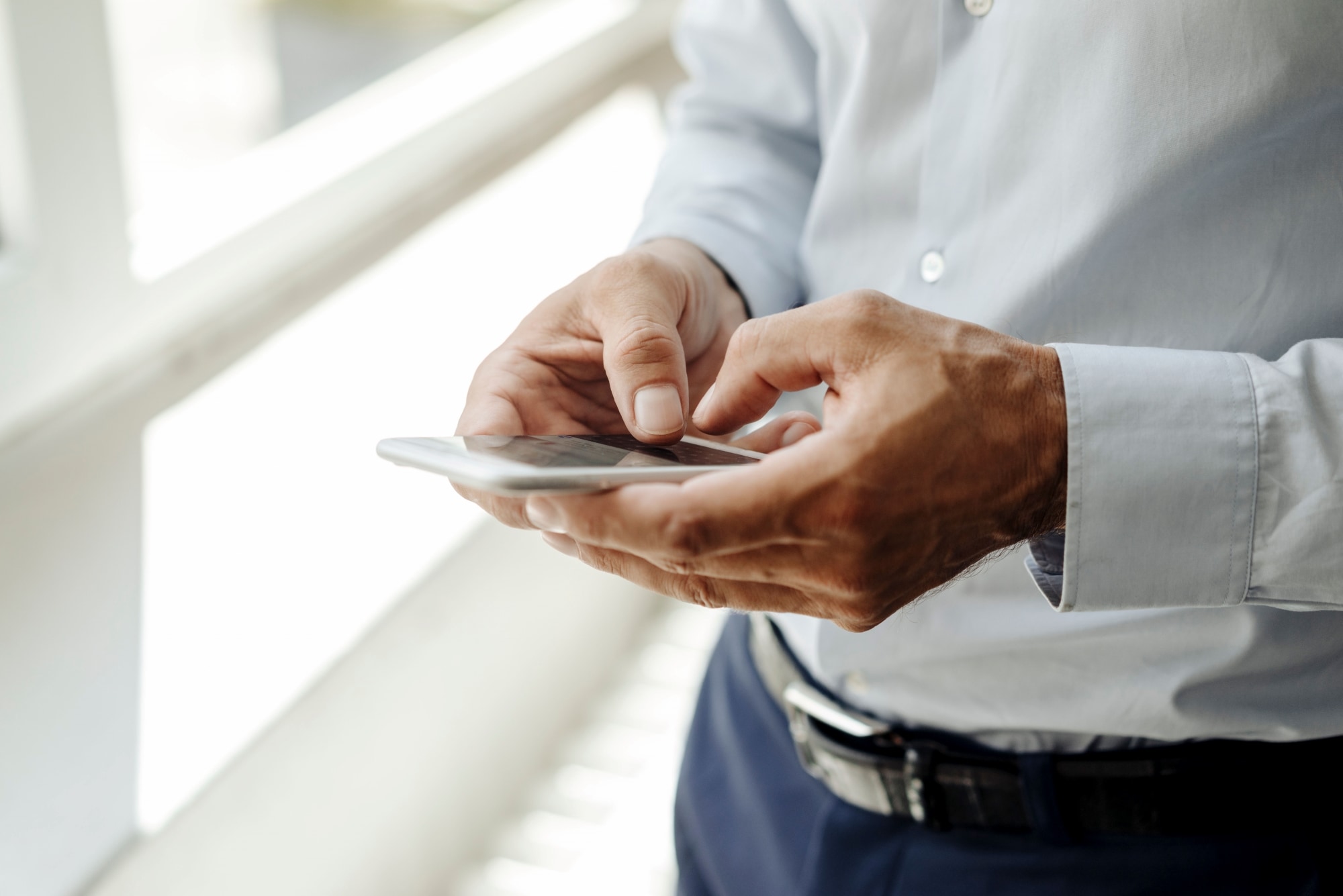 Image of an automated manufacturing assembly line featuring robotic arms and sensors mounted on metal frames, positioned along a conveyor belt, with a focus on precision machinery in a high-tech industrial setting. 