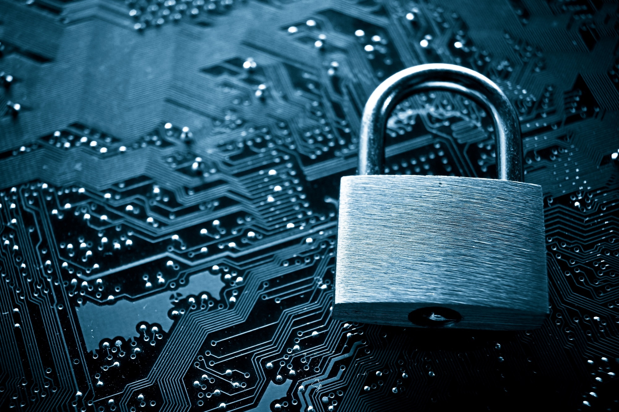 A silver padlock resting on a dark blue circuit board 