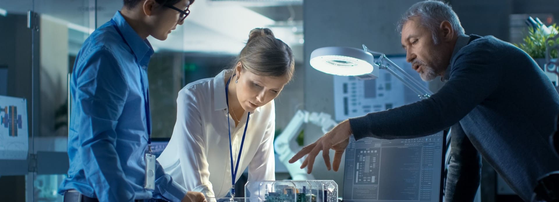 Three engineers discussing an electronics system consisting of multiple circuit boards