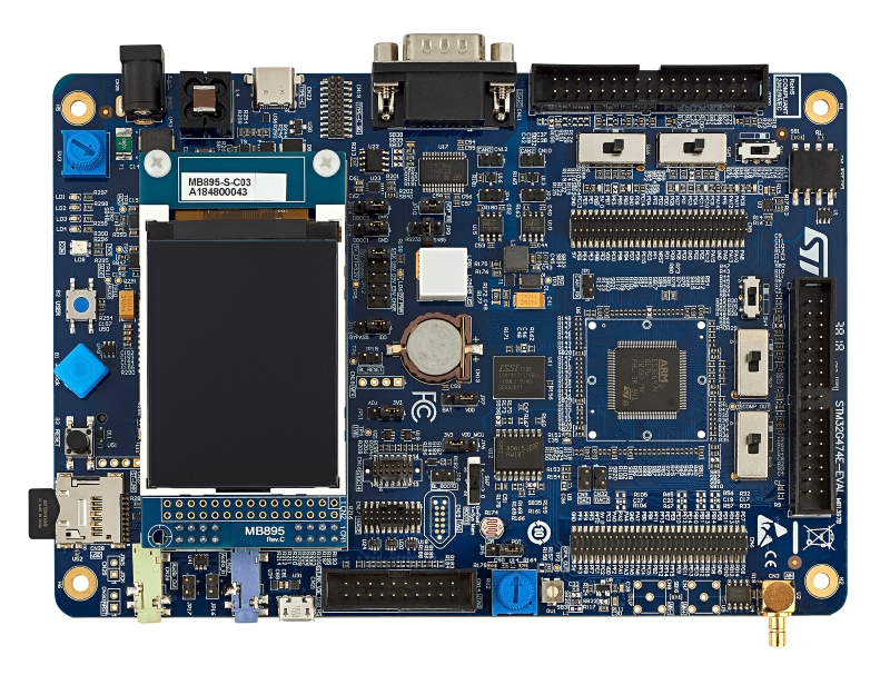 Blue STMicroelectronics evaluation board with display, connectors, and dense components. 